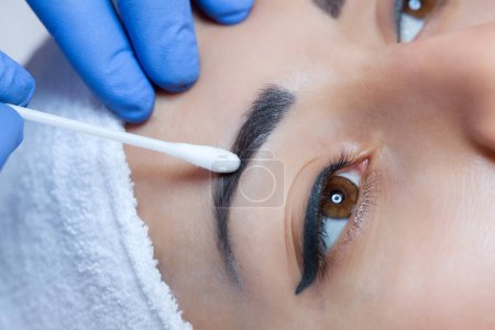 Maquillage permanent pour les sourcils de belle femme aux sourcils épais dans un salon de beauté. Esthéticienne en gros plan faisant tatouer les sourcils.