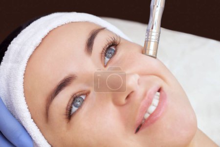 Photo for The cosmetologist makes the procedure Microdermabrasion of the facial skin of a beautiful, young woman in a beauty salon.Cosmetology and professional skin care. - Royalty Free Image