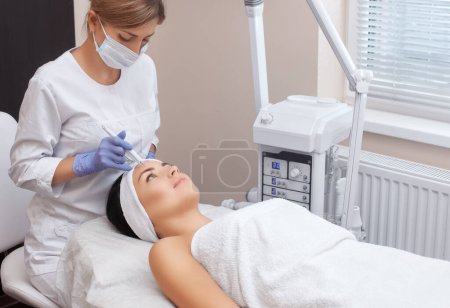 Photo for The doctor-cosmetologist makes the procedure treatment of Couperose of the facial skin of a beautiful, young woman in a beauty salon.Cosmetology and professional skin care. - Royalty Free Image