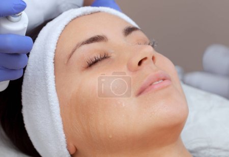 Téléchargez les photos : La procédure de vaporisation de la peau du visage d'une jeune femme avant le nettoyage de la peau dans un salon de cosmétologie
. - en image libre de droit