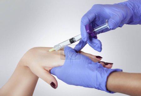 Téléchargez les photos : Le médecin fait des injections intramusculaires de toxines botuliniques mains d'une femme. - en image libre de droit