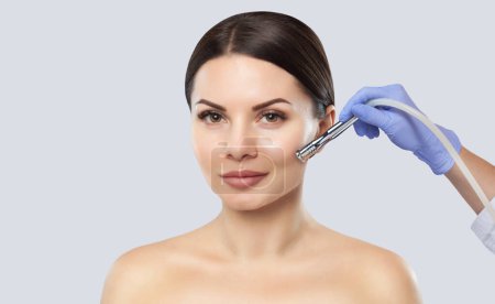 Téléchargez les photos : Il ya une femme, qui fait la procédure Microdermabrasion de la peau du visage dans un salon de beauté.. - en image libre de droit