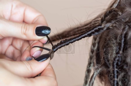 Foto de Una peluquera teje rastas a una hermosa joven en un peluquero.Hermosos peinados. - Imagen libre de derechos