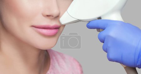 Photo for The cosmetologist does the procedure for laser hair removal of unwanted hair of the face to a young girl in a beauty salon. - Royalty Free Image