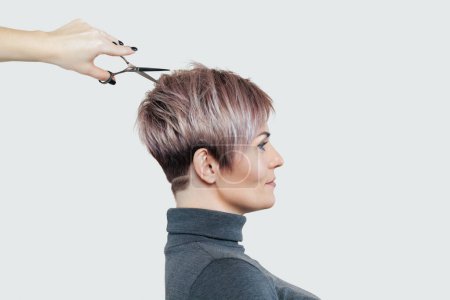 Téléchargez les photos : Coiffeur fait une coupe de cheveux créative à une belle femme chez le coiffeur. Soins capillaires professionnels et création de coiffures. - en image libre de droit
