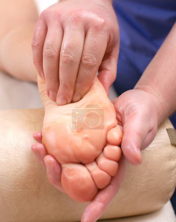 Téléchargez les photos : Un médecin orthopédique fait un massage du pied et du bas de la jambe du patient après une blessure à la cheville entorse dans la clinique.Cosmétologie et concept de massage. - en image libre de droit