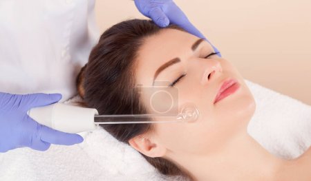 Terapia microactual de la piel facial de una hermosa mujer joven en un salón de belleza. Cosmetología y cuidado profesional de la piel.