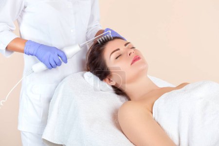 Téléchargez les photos : Le cosmétologue fait la thérapie Microcurrent contre la perte de cheveux sur les cheveux dans un salon de beauté.. - en image libre de droit