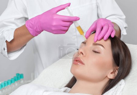 Photo for Cosmetologist does prp therapy on the face of a beautiful woman in a beauty salon. Cosmetology concept. - Royalty Free Image