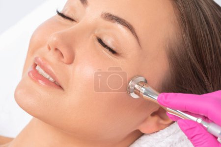 Téléchargez les photos : Le cosmétologue effectue la procédure Microdermabrasion de la peau du visage d'une belle fille dans un salon de beauté.. - en image libre de droit