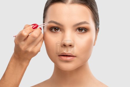 Maquillaje artista peina y arranca las cejas después de teñir en un salón de belleza. Maquillaje profesional y cosmetología cuidado de la piel.