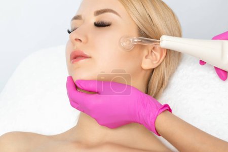 Photo for The doctor-cosmetologist makes the Microcurrent therapy procedure of a beautiful, young woman in a beauty salon.Cosmetology and professional skin care. - Royalty Free Image