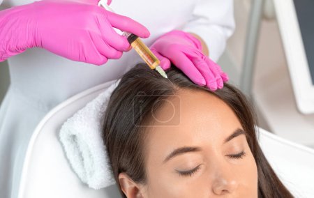 Téléchargez les photos : Cosmetologue fait prp thérapie contre la perte de cheveux et anti-pellicules d'une belle femme dans un salon de beauté. Concept cosmétologie. - en image libre de droit