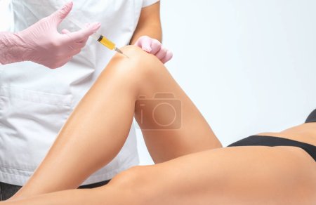 Arzt bei der Stammzellentherapie am Knie eines Patienten nach der Verletzung. Knieschmerzen mit plättchenreicher Plasmainjektion behandeln. Behandlung von Arthritis und Arthrose. Medizinisch-kosmetologisches Konzept.