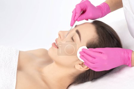 Photo for A procedure for cleansing the skin of the face from blackheads and acne. Cosmetologist treats problematic skin of a young woman's face in a beauty salon. Aesthetic cosmetology and makeup concept. - Royalty Free Image