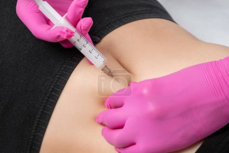 doctor of aesthetic cosmetology makes lipolytic injections to burn body fat on a womans stomach and body. Female aesthetic cosmetology in a beauty salon.