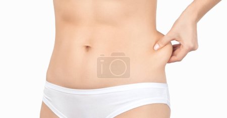 Foto de La niña tira de la piel en el abdomen, mostrando la grasa corporal en el área abdominal y los lados. Tratamiento y eliminación del exceso de peso, depósito de grasa subcutánea. - Imagen libre de derechos