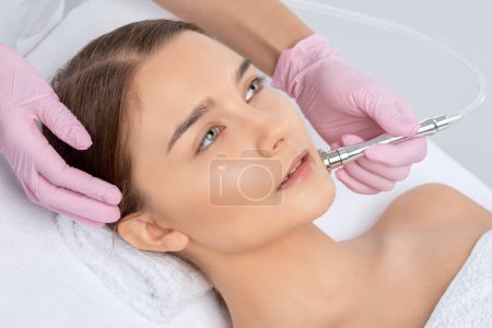 Téléchargez les photos : Le cosmétologue effectue la procédure Microdermabrasion de la peau du visage d'une belle fille dans un salon de beauté.. - en image libre de droit
