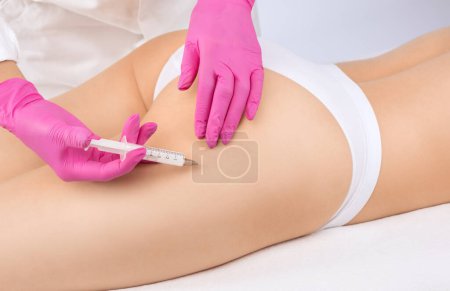 Kosmetologe macht lipolytische Injektionen, um Fett an den Oberschenkeln, Hüften und Körper einer Frau zu verbrennen. Weibliche ästhetische Kosmetologie im Schönheitssalon. Kosmetologie-Konzept.