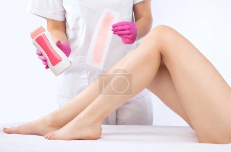 Eine Kosmetikerin macht in einem Schönheitssalon eine Epilation der Beine einer Frau mit Zuckerpaste. Weibliche ästhetische Kosmetologie.