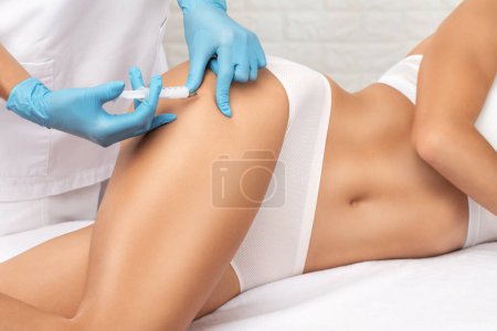 cosmetologist makes lipolytic injections to burn fat on the thighs, hips and body of a woman. Female aesthetic cosmetology in a beauty salon.Cosmetology concept.