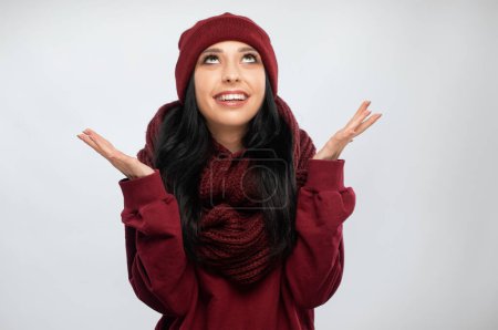 Cheerful and emotional  brunette girl with beautiful makeup, with clean skin, long hair in a burgundy  winter sweater and in a hat . New Year concept