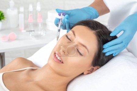 Cosmetologue fait rajeunissant anti rides injections sur le visage d'une belle femme. Cosmétologie esthétique féminine dans un salon de beauté.