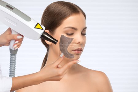 Kosmetikerin macht Laser-Carbon-Peeling auf den Problemzonen der Haut eines jungen schönen Mädchens. Kosmetologie und professionelle Hautpflege.