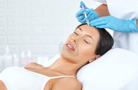 Cosmetologue fait rajeunissant anti rides injections sur le visage d'une belle femme. Cosmétologie esthétique féminine dans un salon de beauté.