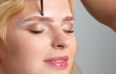 Foto de El maquillador hace las marcas para las cejas y pinta las cejas. Maquillaje profesional y cuidado facial. - Imagen libre de derechos