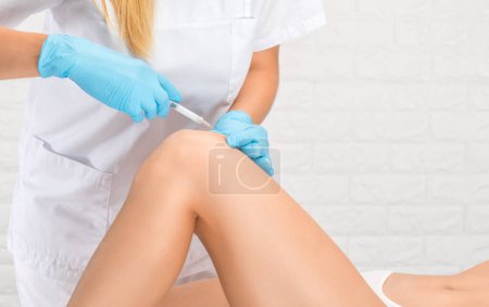 Photo for Doctor doing stem cell therapy on a patient's knee after the injury. Treating knee pain with platelet-rich plasma injection. Treatment of arthritis and osteoarthritis.Medical and cosmetology concept. - Royalty Free Image
