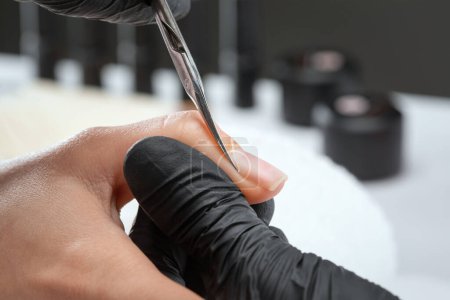 A manicurist removes cuticles during a nail extension procedure in a beauty salon. Professional hand care.