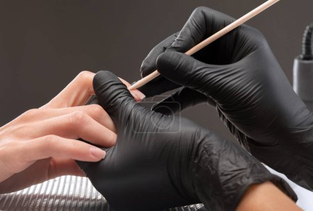 Eine Maniküre entfernt Nagelhaut während einer Nagelverlängerung in einem Schönheitssalon. Professionelle Handpflege.