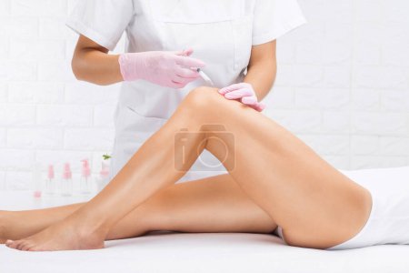 epilation hair removal procedure on a womans body. Beautician doing laser rejuvenation on the lower leg in a beauty salon. Removing unwanted body hair. Hardware ipl cosmetology