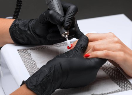 The master of the manicure saws and attaches a nail shape during the procedure of nail extensions in the beauty salon. Professional care for hands.