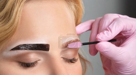 Foto de El maquillador hace las marcas con el lápiz blanco para las cejas y pinta las cejas. Maquillaje profesional y cuidado facial. - Imagen libre de derechos