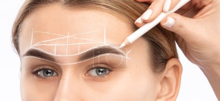 El maquillador hace las marcas con el lápiz blanco para las cejas y pinta las cejas. Maquillaje profesional y cuidado facial.