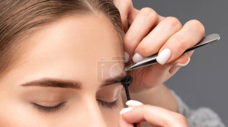 Foto de Maquillaje artista arranca las cejas en un salón de belleza. Maquillaje profesional y cuidado cosmético de la piel. - Imagen libre de derechos
