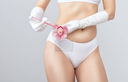 Téléchargez les photos : Une femme tient une orchidée rose dans ses mains et fait des injections pour rajeunir. Le concept de chirurgie plastique. - en image libre de droit