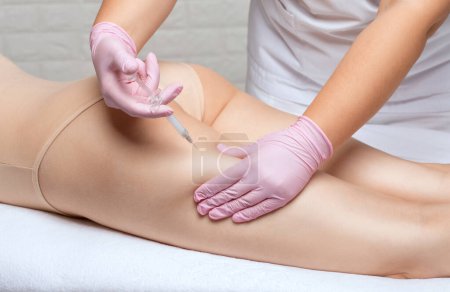 lipolytic injections to burn body fat on a womans hips, legs and thighs. Female aesthetic cosmetology in a beauty salon.