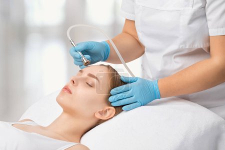 Photo for Cosmetologist makes procedure microdermabrasion on the face against acne and blackheads near the eyes. Women's cosmetology in the beauty salon. - Royalty Free Image