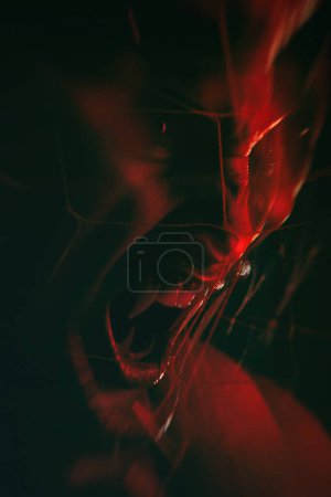 Retrato cercano de una chica vampiro con colmillos largos sobre un fondo rojo.