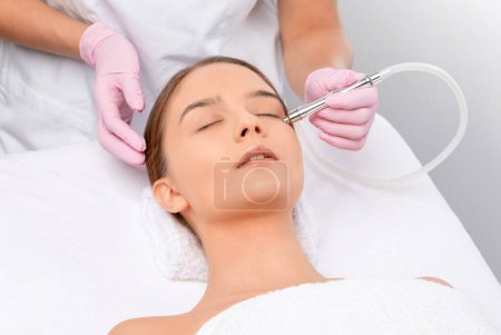 Photo for Procedure microdermabrasion on the face against acne and blackheads. Women's cosmetology in the beauty salon. - Royalty Free Image