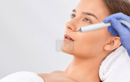 El cosmetólogo hace el tratamiento del procedimiento de Couperose de la piel facial de una mujer hermosa, joven en un salón de belleza. Cosmetología y cuidado profesional de la piel
.