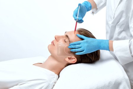 Men's cosmetology. Beautician makes a man a rejuvenation injection procedure on his face.