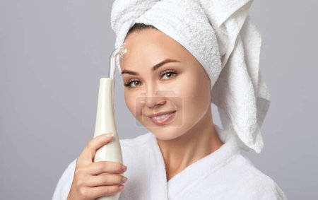Foto de La mujer joven hace el procedimiento Terapia microactual de la piel facial. Cosmetología y cuidado profesional de la piel. - Imagen libre de derechos