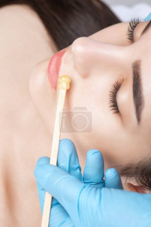 Maquillaje artista hace procedimiento de depilación facial. Eliminación de bigote con cera.