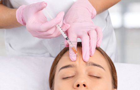 El cosmetólogo hace rejuvenecedoras inyecciones antiarrugas en la cara de una mujer hermosa. Cosmetología estética femenina en un salón de belleza.