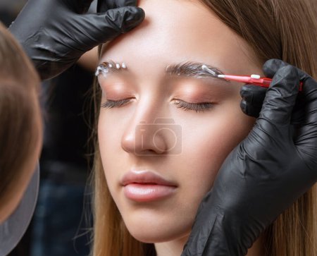 The make-up artist does Long-lasting styling of the eyebrows of the eyebrows and will color the eyebrows. Eyebrow lamination. Professional make-up and face care.