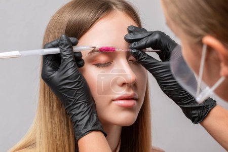 Foto de Maquillaje artista hace marcas para las cejas antes de teñir a una hermosa joven en un salón de belleza. Maquillaje profesional y cuidado facial. - Imagen libre de derechos